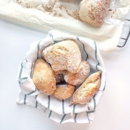 pão caseiro em cesto com pano de cozinha branco e verde